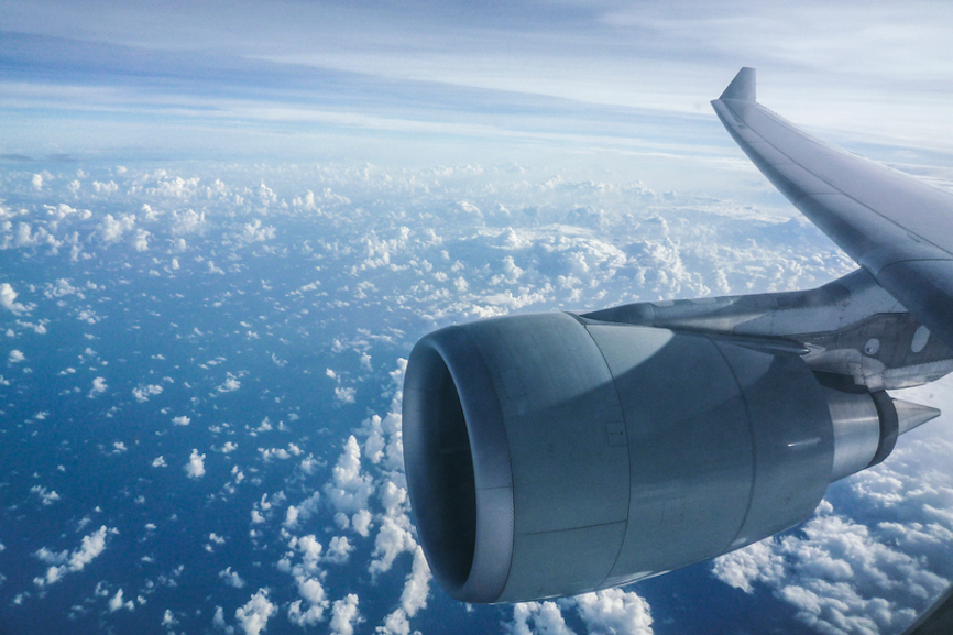 Aircraft engine and wing flying over sky full of clouds used in Travel with Jane post on Onboard travel bag packing